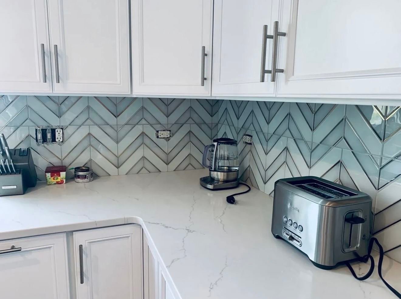 Chevron pattern tile backsplash in a white kitchen