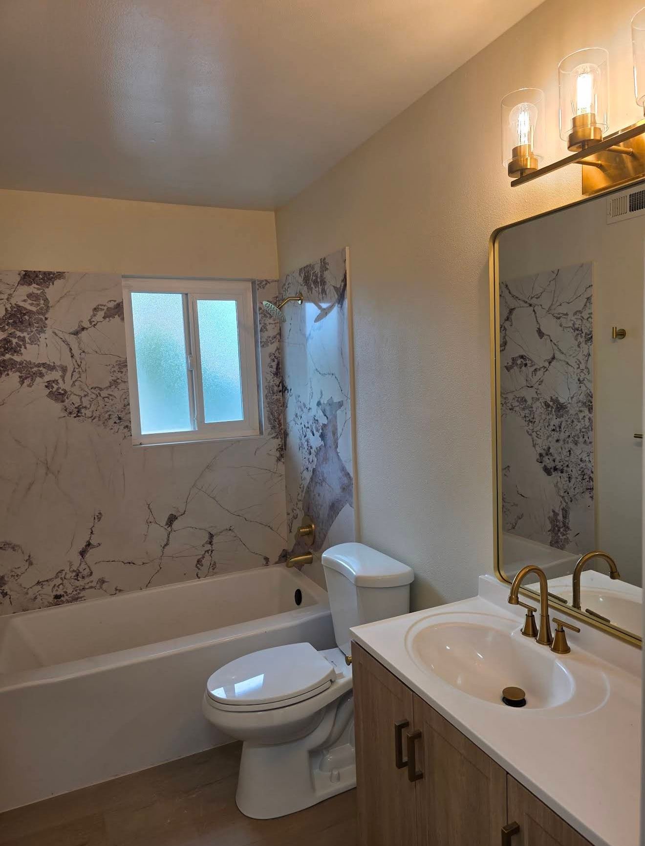 Bathroom with veined marble tub surround and brass fixtures