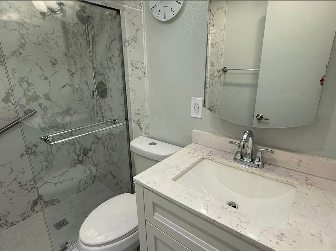 White marble bathroom with standing shower and white vanity