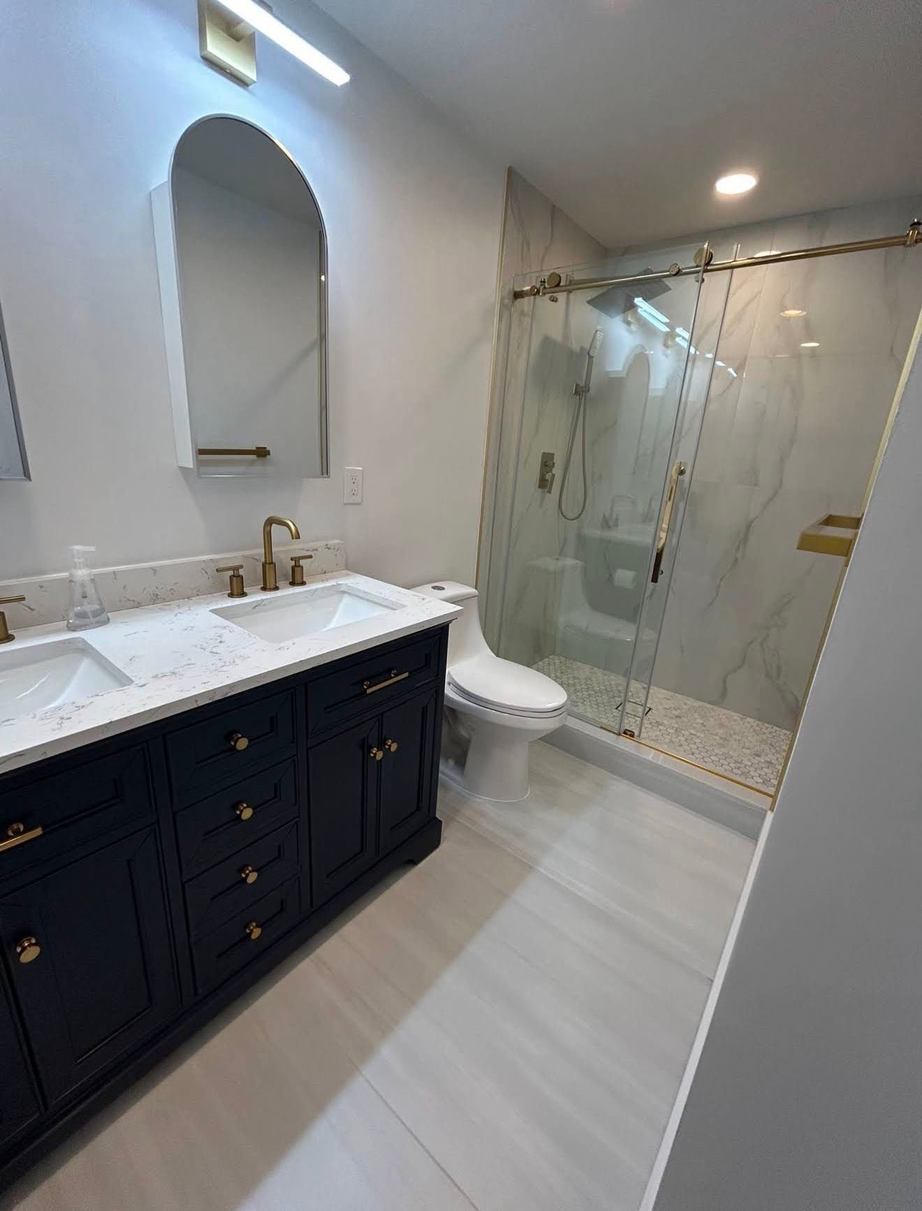 Navy vanity with gold hardware and glass marble shower